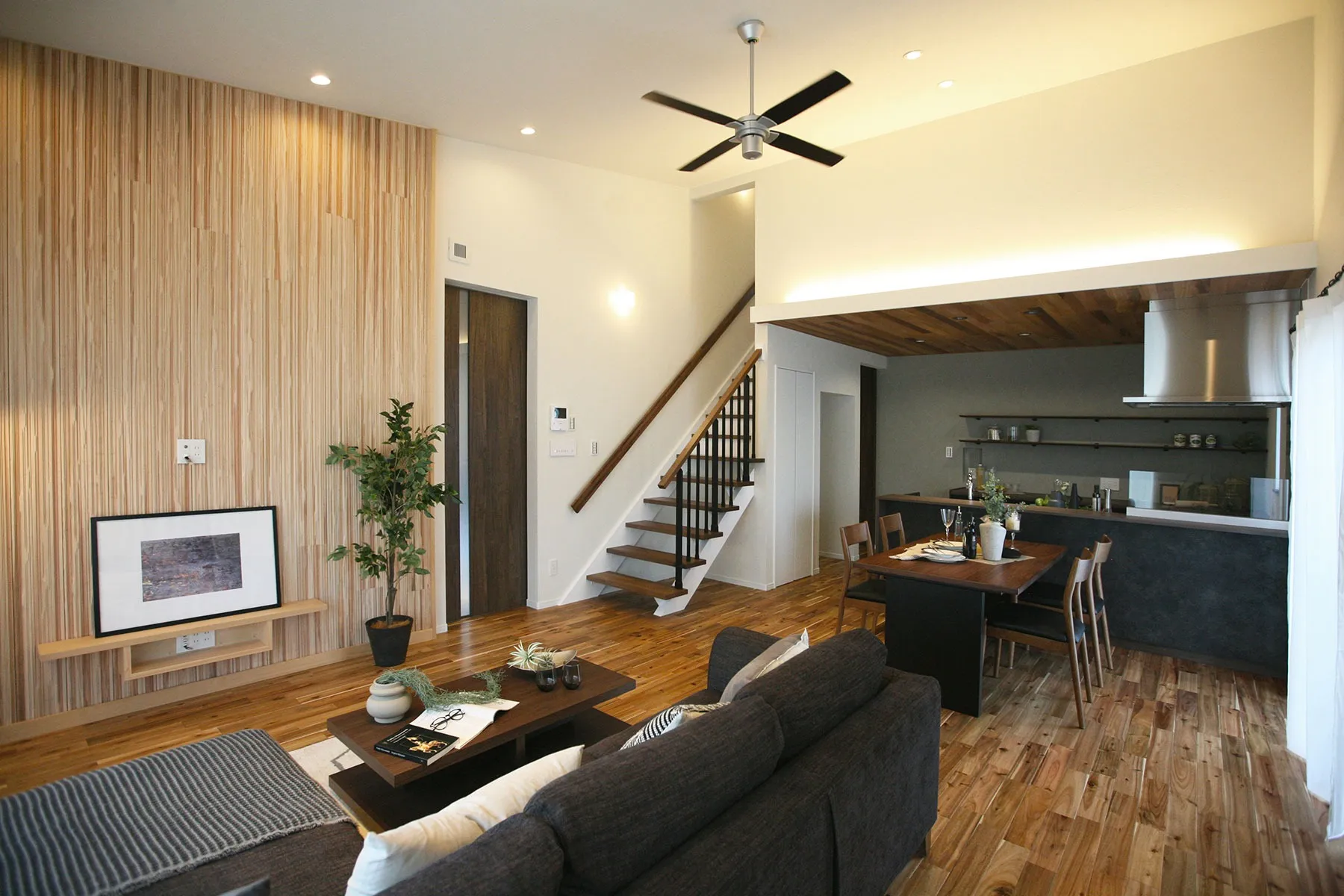 多種多様な木目を使用した天井の高いリビング・ダイニングのある家<br width=